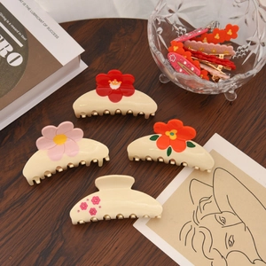 Lot de quatre pinces à cheveux à fleurs en acétate sur une table en bois