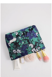 Detailed view of vintage floral jacquard makeup bag with zipper and logo label