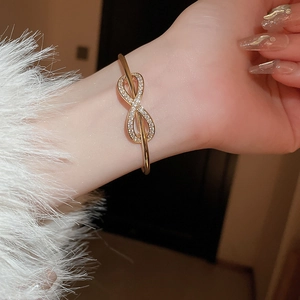 Close-up of gold plated bowknot infinity bracelet with sparkling cubic zirconia on wrist
