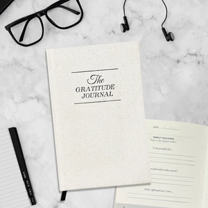 Beige linen Gratitude Journal A5 notebook displayed on marble background with lifestyle props