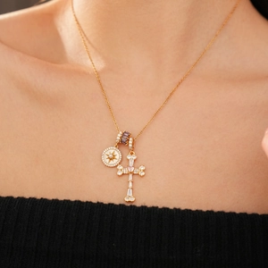 Detail of 18k gold cross necklace with pink heart gem and star coin on neck