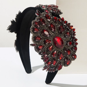Macro view of Baroque style headband with dark red crystals on black velvet base