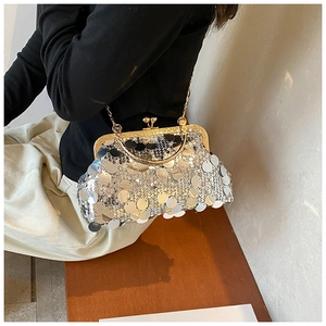 Detail of silver sequin crossbody bag with gold metal clasp and chain strap on a model