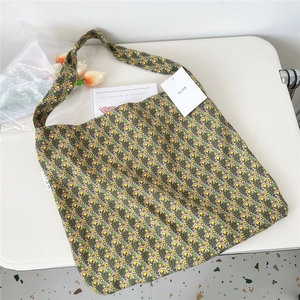 Detail of floral canvas tote bag with lemon pattern on white desk with tulips