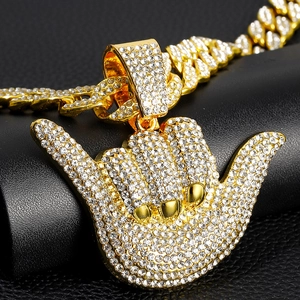 Close-up of golden Shaka 666 pendant with clear rhinestones on iced out Cuban chain