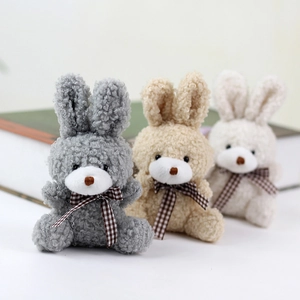 Detailed view of plush rabbit pendants in grey, beige and cream with plaid bow ties