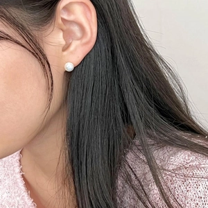 Close-up of a 925 sterling silver pearl stud earring worn on a female model's ear