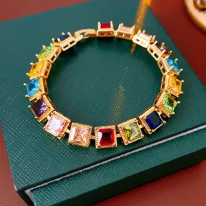 Bracelet vintage en or avec zircons carrés colorés sur une boîte à bijoux en cuir vert