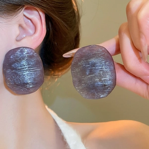 Detail shot of purple round earrings with brushed texture on model to show fit and size