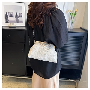 Detail of elegant white sequined evening bag with a gold chain strap and beads