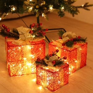 Close-up of three red lighted Christmas gift boxes with golden bows and warm LED lights