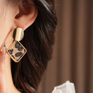 Gros plan de boucles d'oreilles géométriques dorées à motif léopard sur mannequin