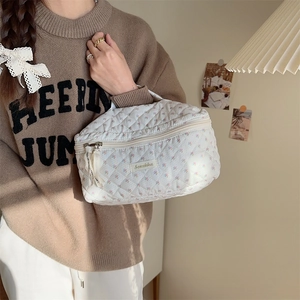 Close-up of a white quilted floral makeup bag with a top zipper and a sturdy handle