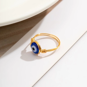 Macro shot of gold wire-wrapped ring featuring a blue evil eye bead detail