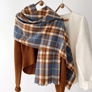 Detail of blue and brown plaid oversized scarf with short fringe and soft cashmere-like texture