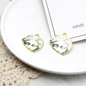 Macro view of gold-trimmed Medusa head pendants with black and white enamel finish