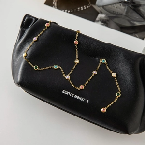 Vue macro du collier en Y doré avec zircons colorés sur texture cuir noir