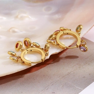 Detail of 18K gold tassels earrings with colorful gemstones on shell texture