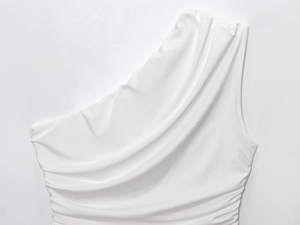 Detailed view of white one-shoulder asymmetric top with elegant ruched fabric texture
