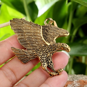 Close-up of golden eagle pendant with detailed feather carving on vintage brass finish