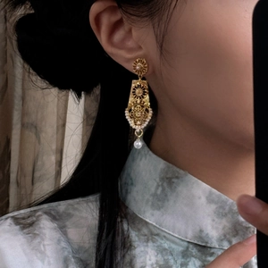 Golden hollowed geometric stud earrings with pearl drop on model for retro style