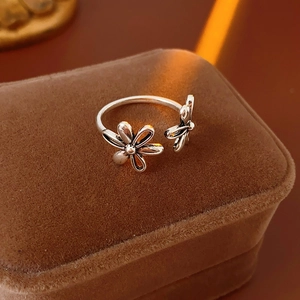 Macro detail of silver floral镂空 adjustable ring on a brown velvet jewelry display