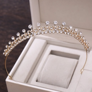 Gros plan d'un diadème de mariée doré avec strass scintillants sur velours blanc