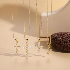 Macro detail of four gold cross necklaces with pearls and zircons on elegant stone props