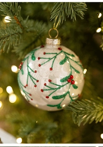 Close-up of hand-painted white glass Christmas ball with red berry motifs on a tree