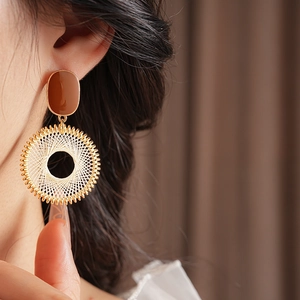 Close-up of vintage round earrings with gold frames and woven cream radial patterns