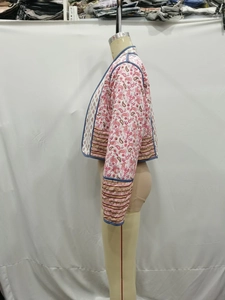 Detail of floral quilted jacket featuring blue piped edges and pink paisley pattern