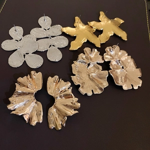 Macro detail of large gold and silver flower petal earrings with brushed metal texture