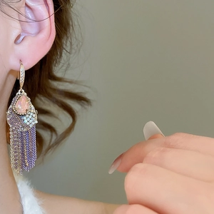 Close-up of long tassel earrings with purple and pink teardrop crystals on model