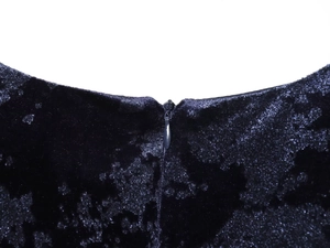 Detailed macro view of the invisible zipper closure on the black velvet midi dress