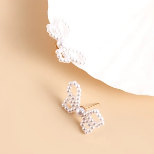 Close-up of handmade faux pearl bow earrings with gold metal stud detail for women