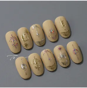 Detail of matte nude nail stickers with gold metallic totem patterns and star moon motifs