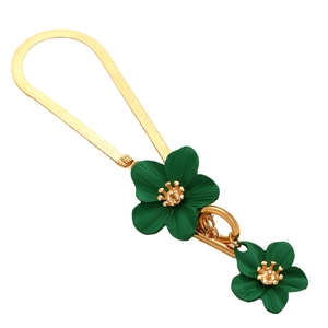 Flat lay of a gold snake chain necklace featuring vibrant green floral pendants with gold centers