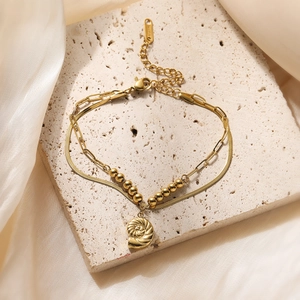 Double-layer 18K gold plated stainless steel bracelet with snail charm on stone background