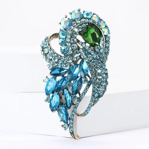 Detailed side view of vintage gold brooch with blue rhinestones and emerald drop stone