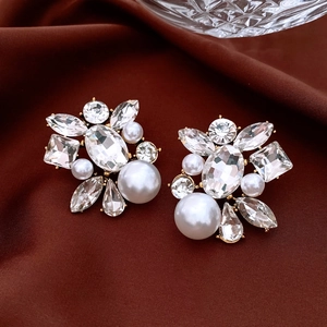 Macro shot of vintage style waterdrop pearl earrings with crystals on brown satin