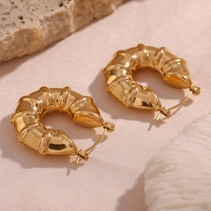 Macro shot of 18K gold plated hoop earrings with hollow tire texture on stone surface
