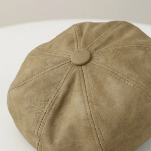 Close-up of khaki leather newsboy cap showing eight-panel stitching and top button