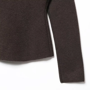 Detailed macro view of dark brown knit texture and premium stitching on the cuff and hem