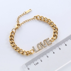 Gold stainless steel Cuban chain bracelet with iced out LOVE letter charm on white background