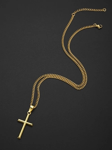 Détail d'une chaîne à maillons cubains dorée avec un pendentif croix sur fond noir mat