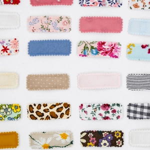 Detail of square snap clips featuring floral embroidery and colorful fabric textures