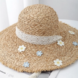 Summer woven straw hat with white lace ribbon and daisy floral details for beach vacation