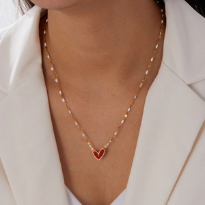 Elegant gold heart pendant necklace with red enamel and white beaded chain detail