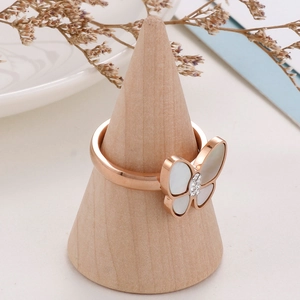 Detail of rose gold butterfly ring with shell inlay and crystals on a wooden stand