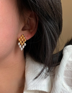 Gros plan de boucles d'oreilles losanges ajourées en zircon portées par un mannequin